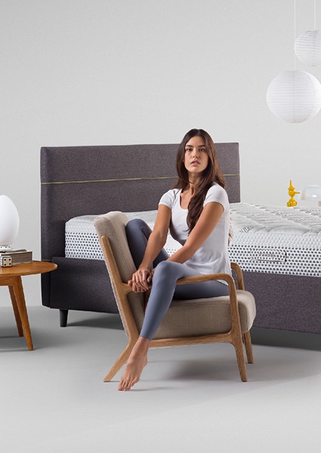 Wellbeing recharge - woman sitting in front of Magniflex mattress